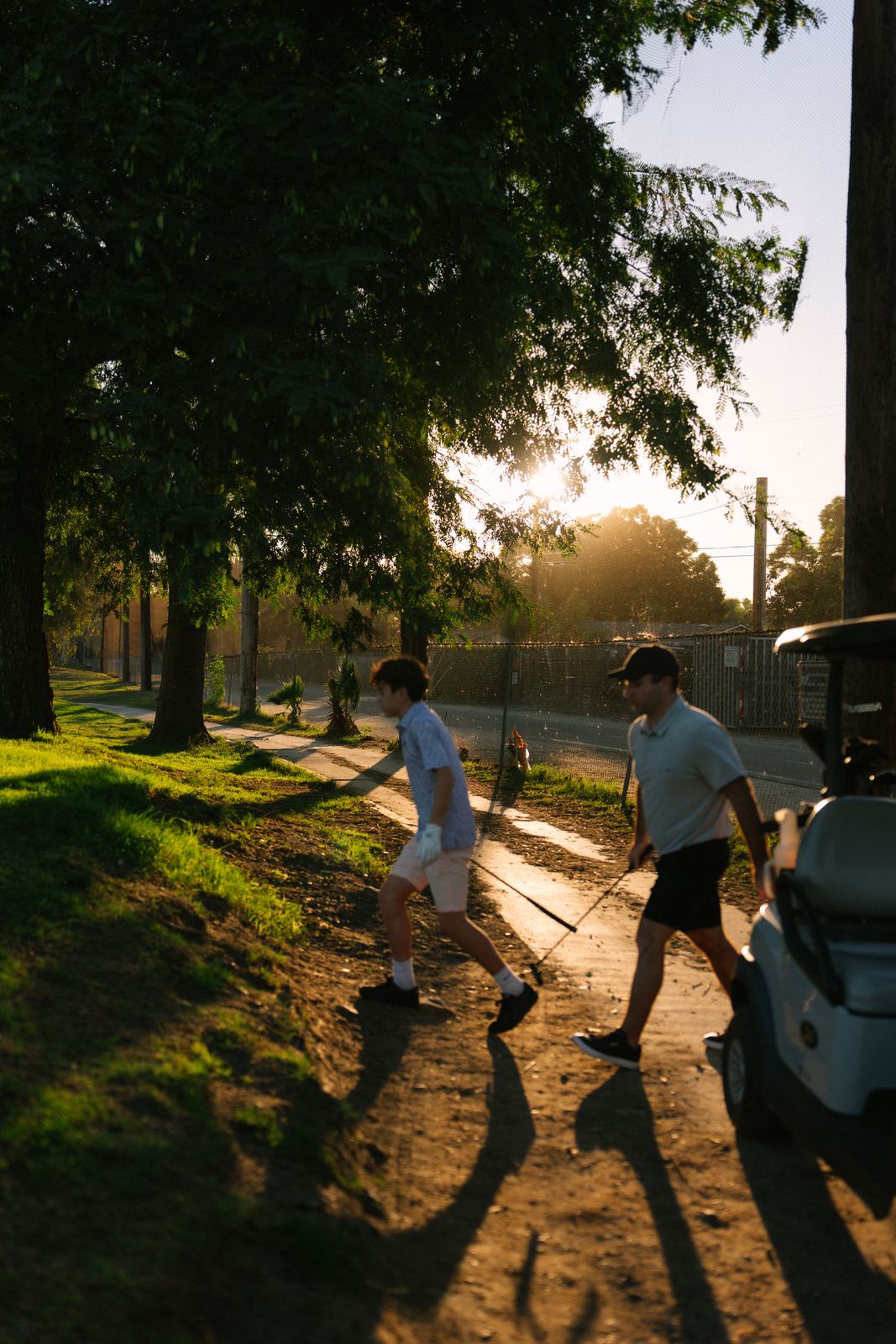 Dad and son walking off the course at sunset