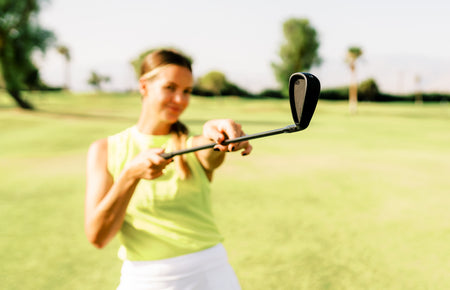 female golfer holding a golf iron