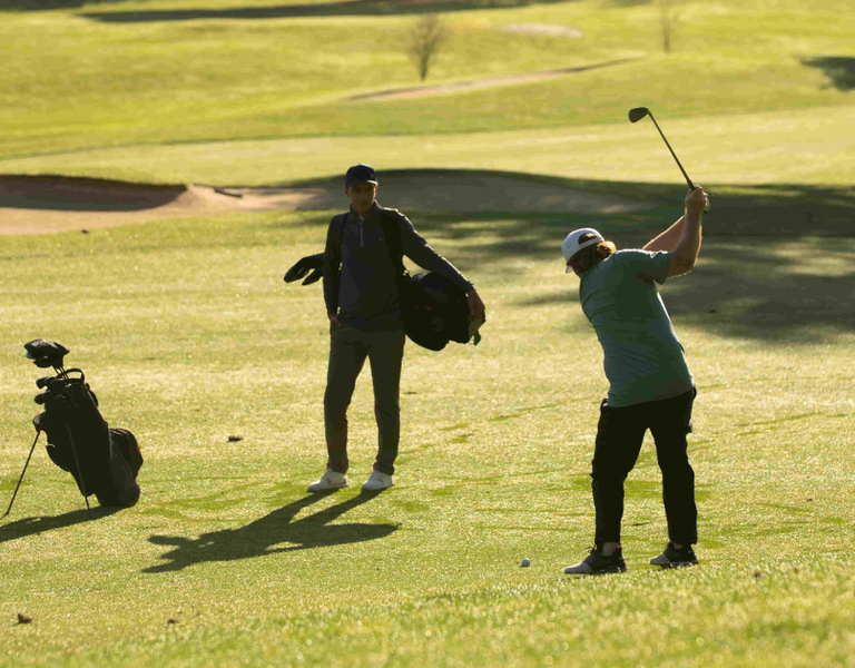 A golfer swinging an iron