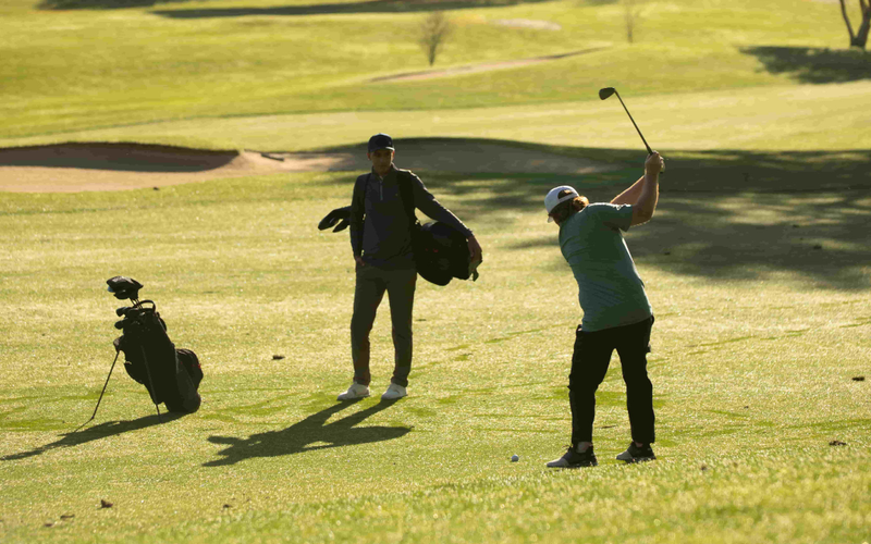 A golfer swinging an iron
