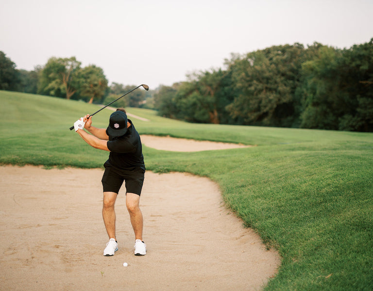 golfer chipping out of sand bunker