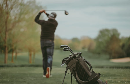 golfer hitting ball with bag behind him