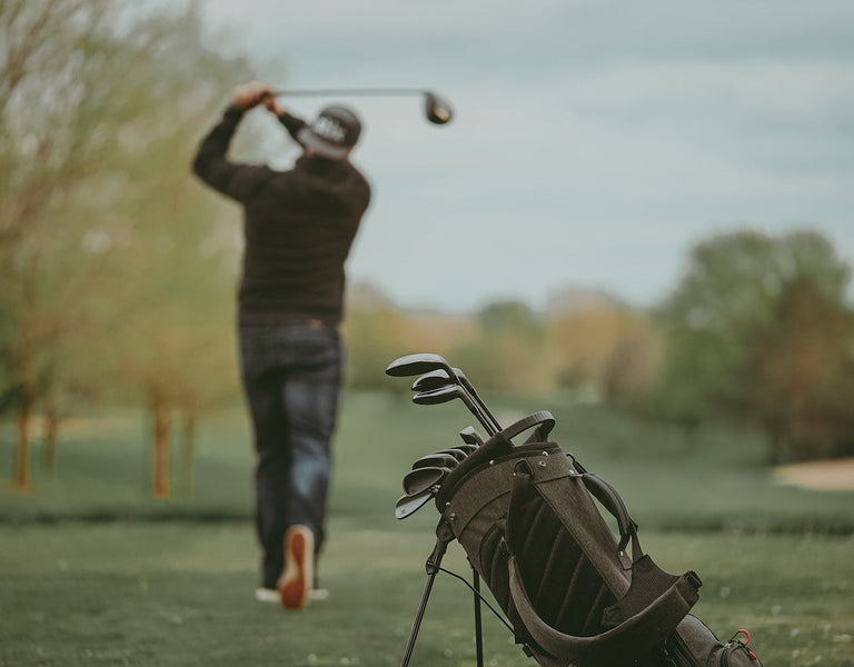 golfer hitting ball with bag behind him