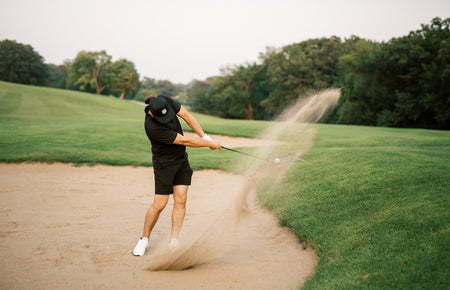 golfer using wedge to get out of sand bunker