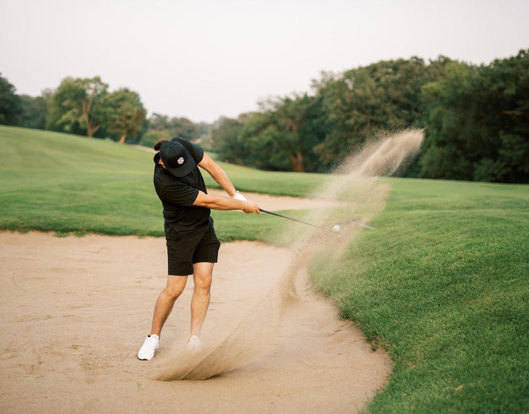 golfer using wedge to get out of sand bunker