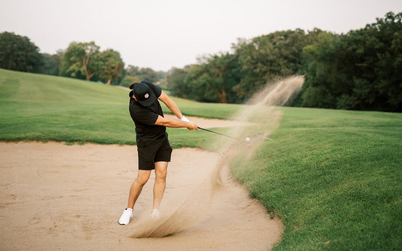 golfer using wedge to get out of sand bunker