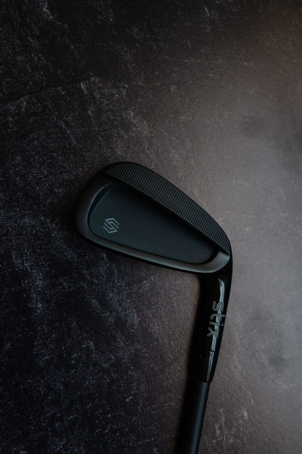 A black Stix cavity-back iron on dark slate