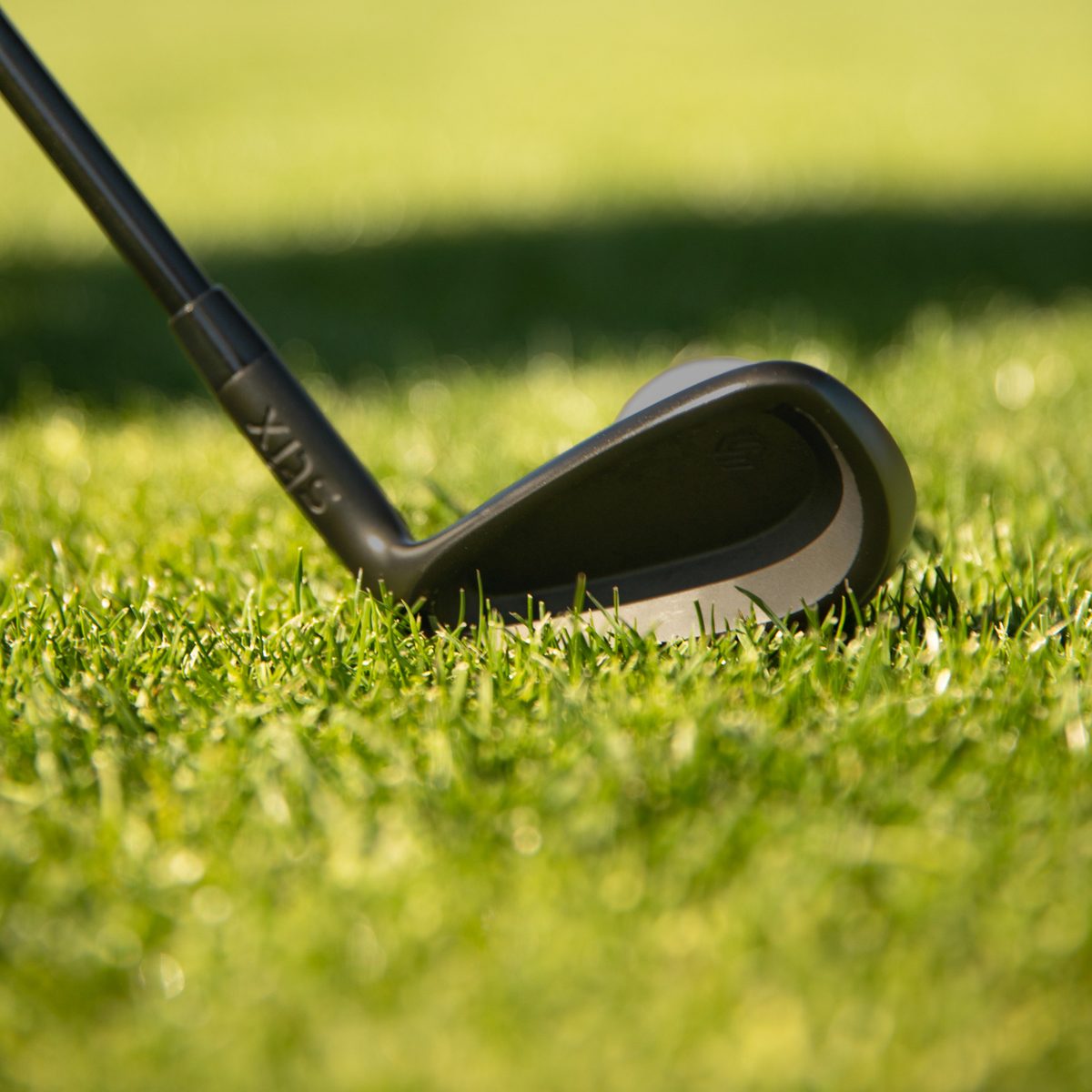 A black Stix cavity-back iron at address in the fairway