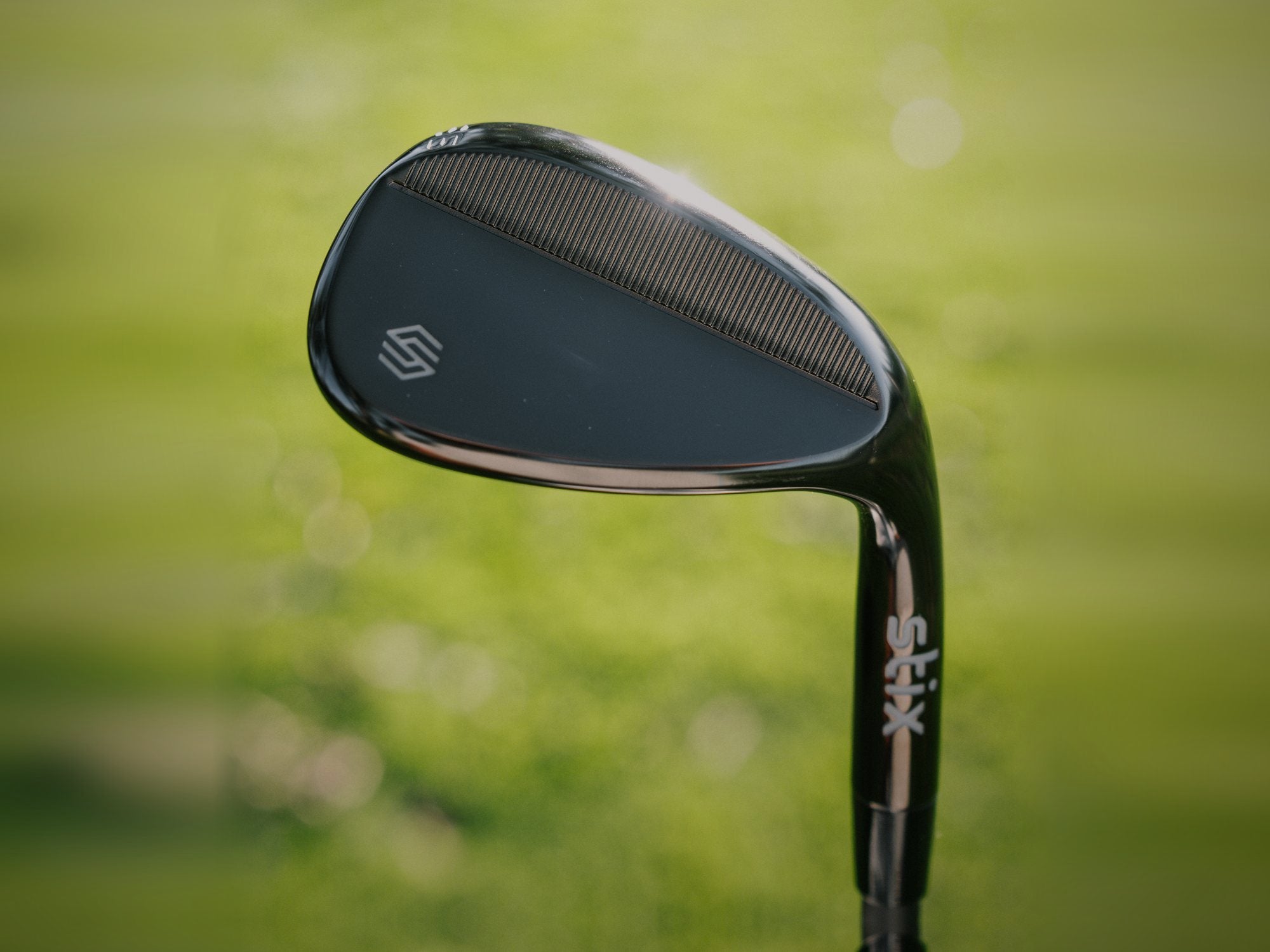 Back of a black Stix Compete wedge against green grass